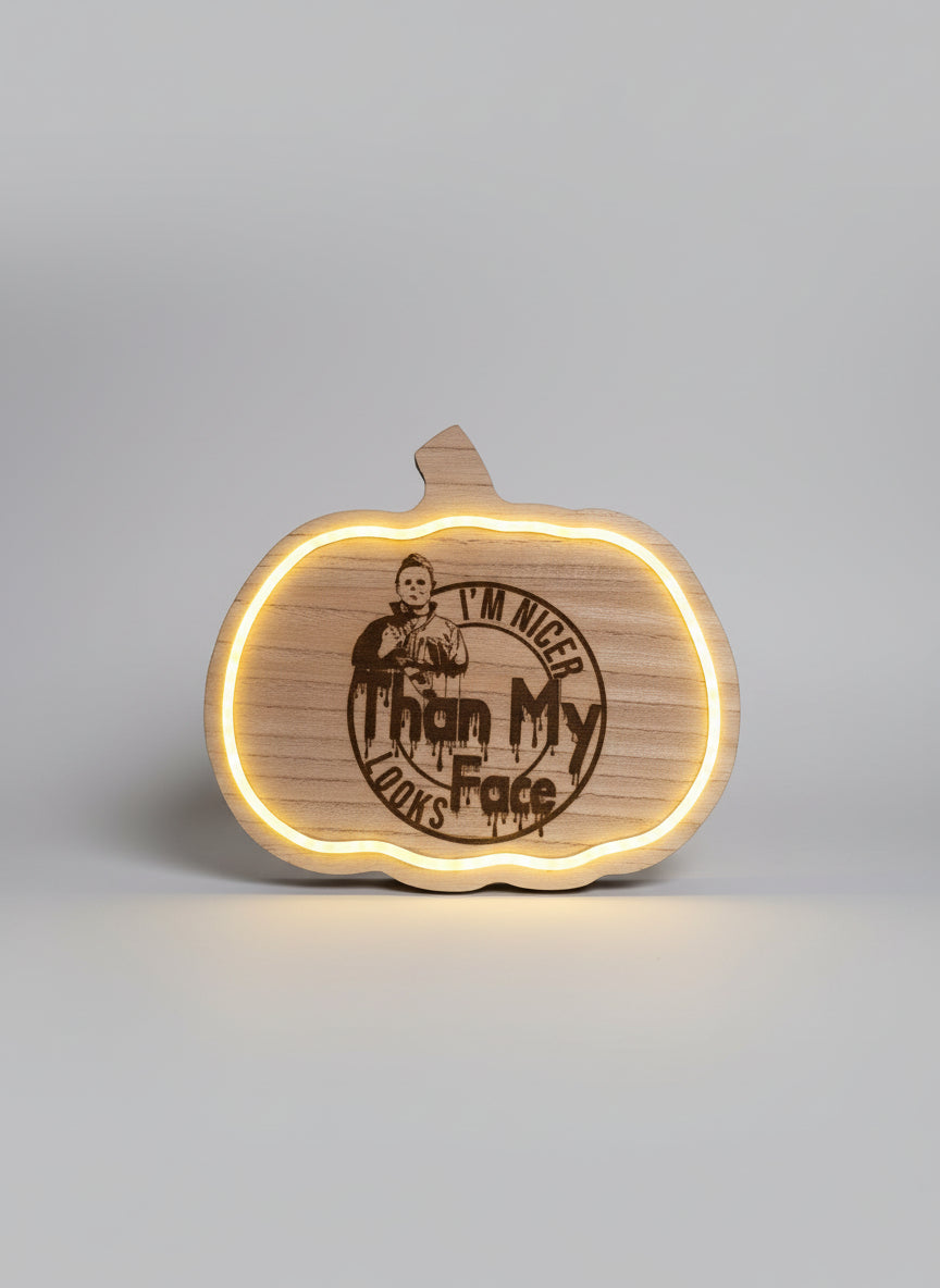 Wooden pumpkin-shaped novelty sign with engraved text and lighting effect on a dark background