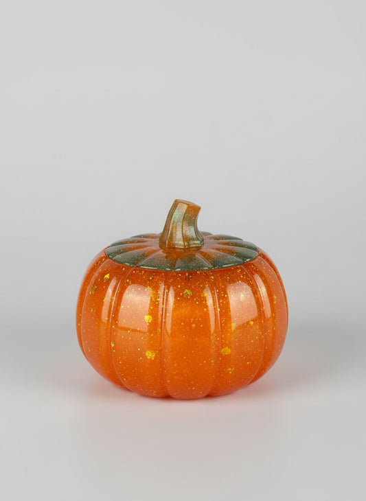 Small orange pumpkin with a green top on a glrey background