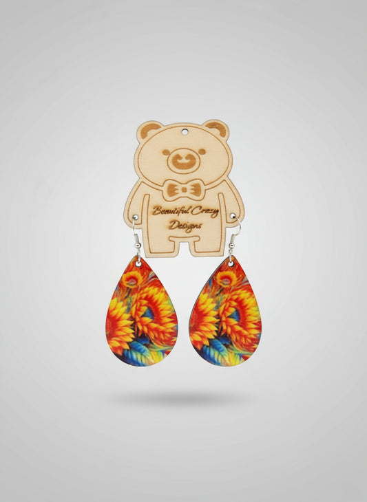 Colorful sunflower teardrop-shaped earrings with a wooden bear-shaped holder on a light gray background.
