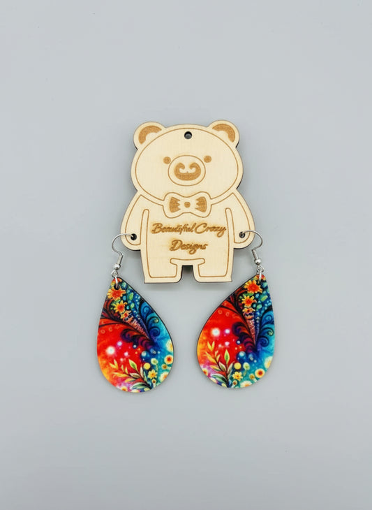 Colorful wildflower teardrop earrings with a bear-shaped pendant on a gray background