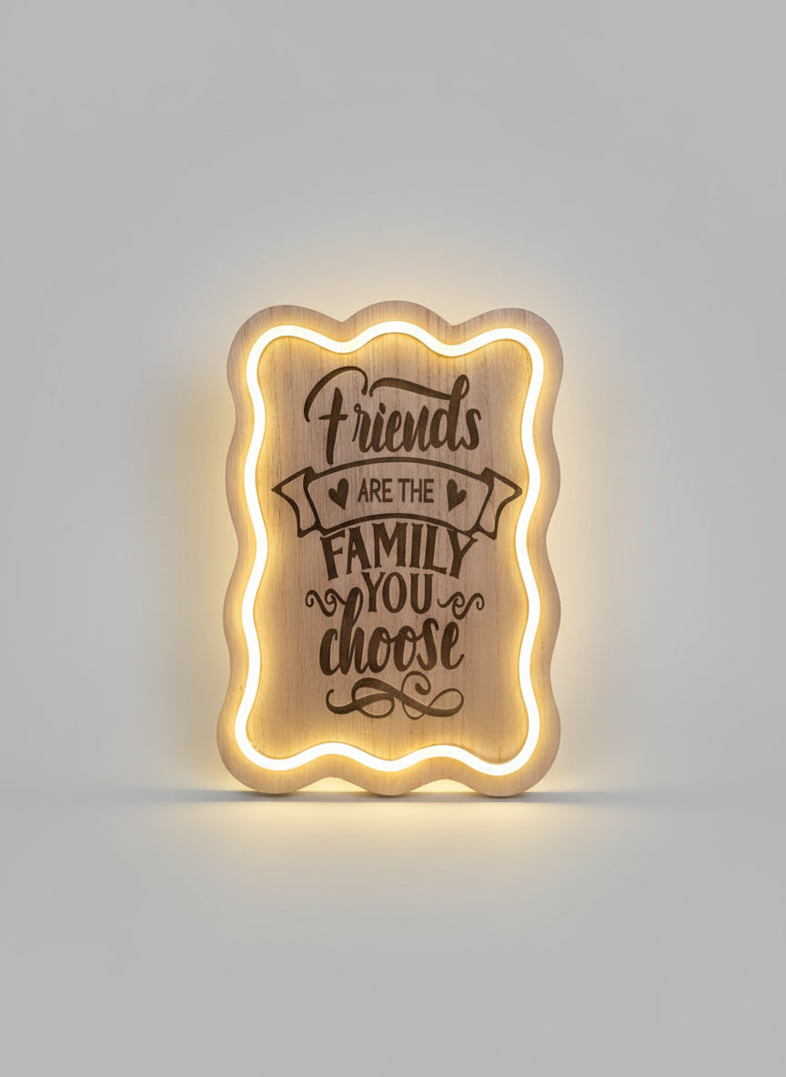 Wooden plaque with engraved text 'Friends are the family you choose' illuminated from behind.