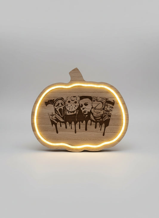 Wooden pumpkin-shaped sign with engraved faces and LED lighting on a dark background
