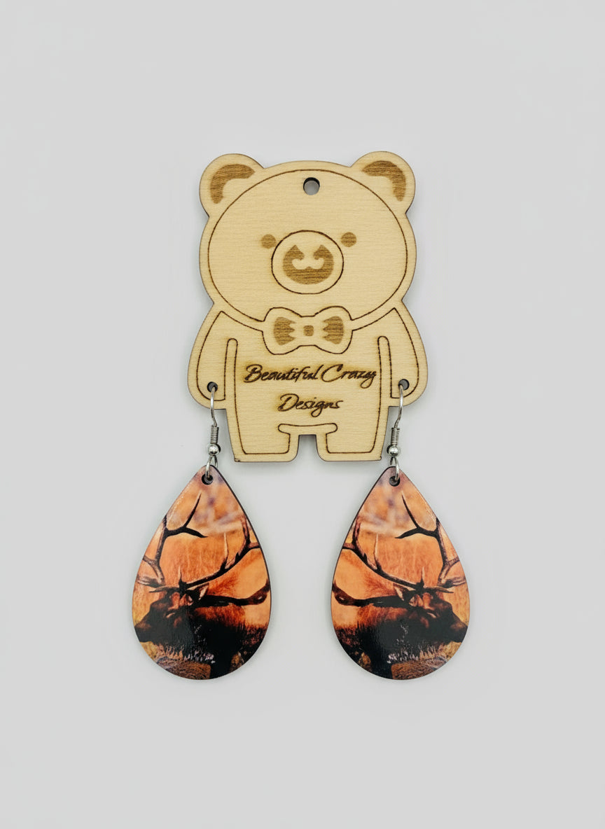 Wooden bear-shaped earring holder with Rocky Mountain elk on teardrop earrings on a light gray background