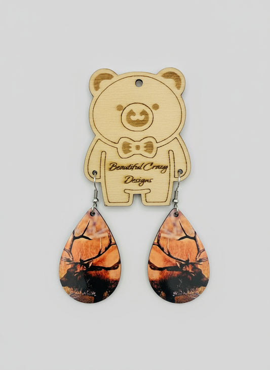 Wooden bear-shaped earring holder with Rocky Mountain elk on teardrop earrings on a light gray background