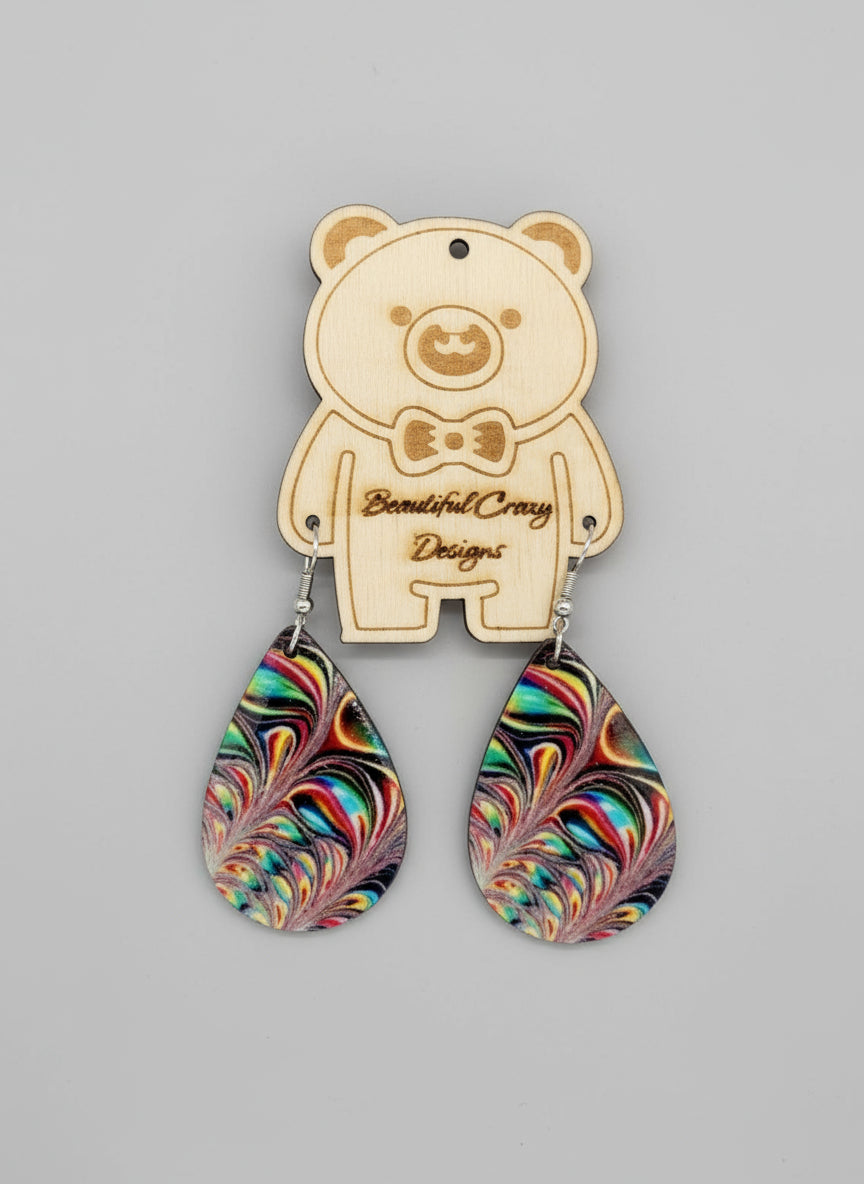 Colorful teardrop earrings with shiny colorful swirls on a bear-shaped pendant on a gray background