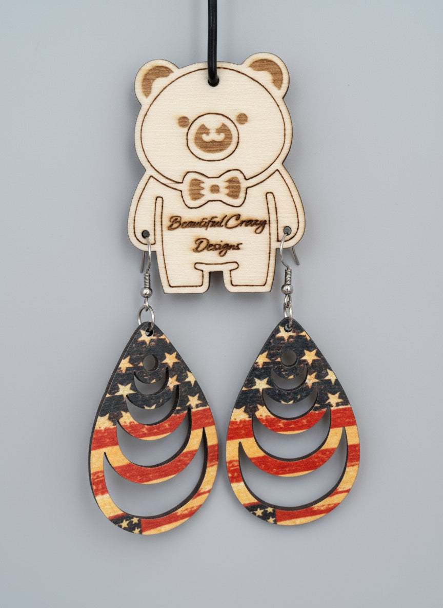 Wooden earrings with American flag design on a wooden background with 'Beautiful Creepy Designs' tag.