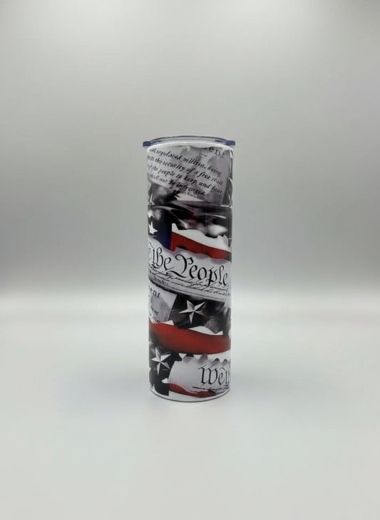 Tumbler with American flag design and text on a grey background.