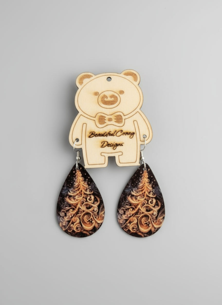 Teardrop-shaped earrings with an intricate white Christmas tree design on a beige bear-shaped card against a gray background.