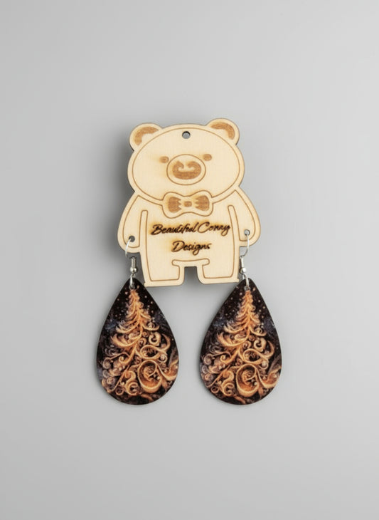 Teardrop-shaped earrings with an intricate white Christmas tree design on a beige bear-shaped card against a gray background.