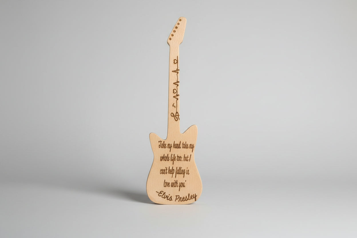 Wooden guitar-shaped decoration with engraved text on a textured wall background