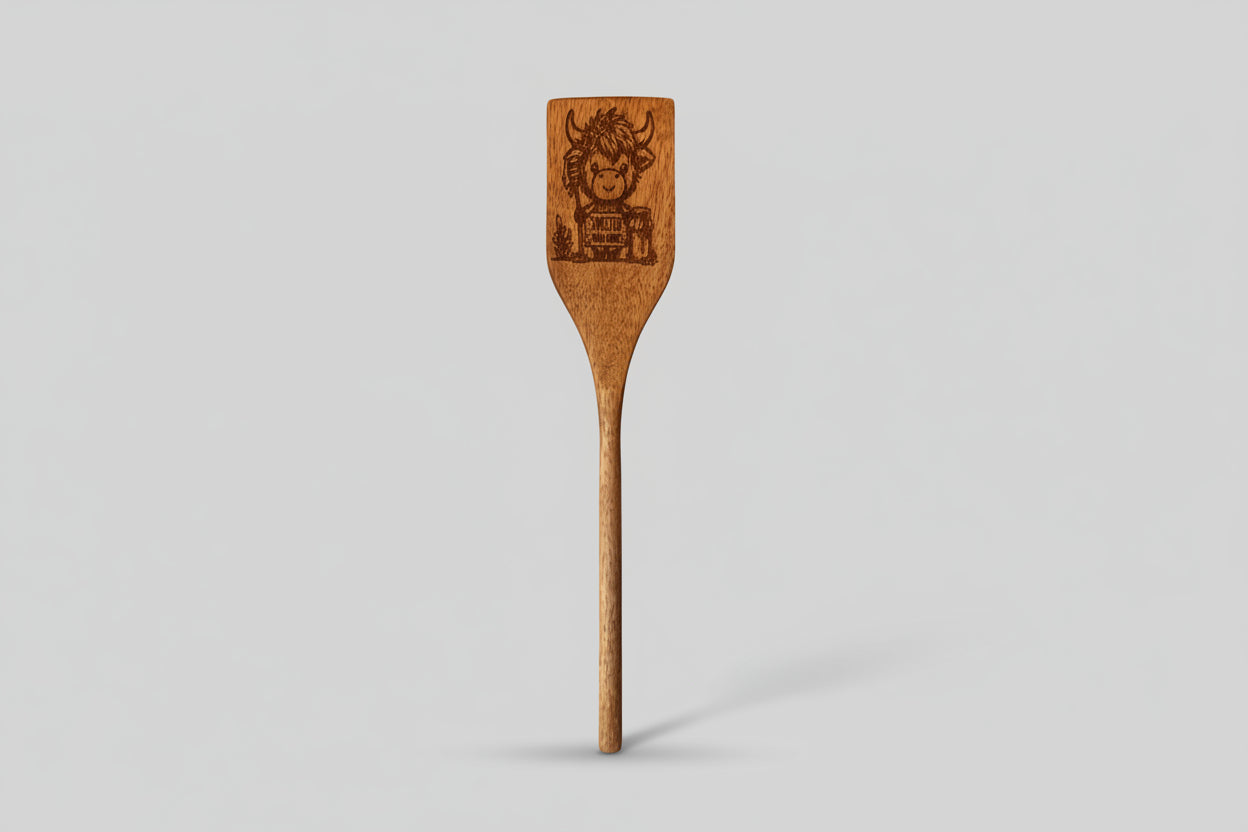Wooden spatula with engraved design on a textured surface