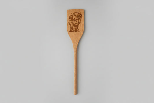 Wooden spatula with engraved design on a textured surface