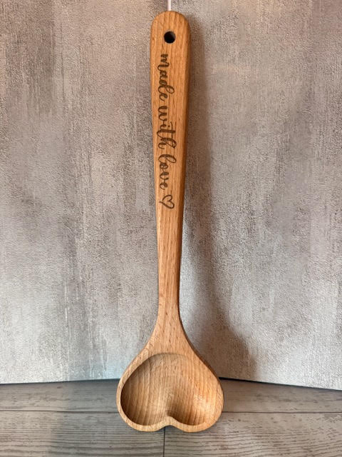 Wooden spoon with engraved text on a neutral background